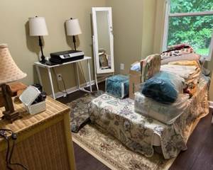 Bedroom with twin mattress, quilts, blankets, lamps, jewelry organizer filled with costume jewelry