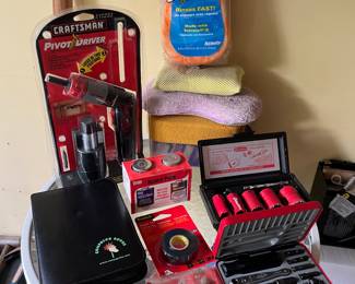 Craftsman pivot driver, Car wash sponges, holesaw drill bit set, combo nut driver/screwdriver set, Screwdriver set in leather case, gauge and electrical tape. all staged on a plant stand/end table.