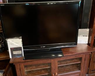 Sony LCD Digital TV and Sharp LCD digital TV mounted on wooden entertainment stand.