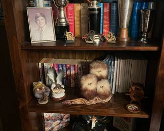 Books, trophies and unusual figurines displayed in one of a 3 piece hutch.