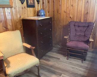 Several pieces left to right: light cream straight chair with Queen Ann fetchers, tall mahogany chest of drawer, Chinese artwork with embossed copper, glider rocker with burgundy cushions