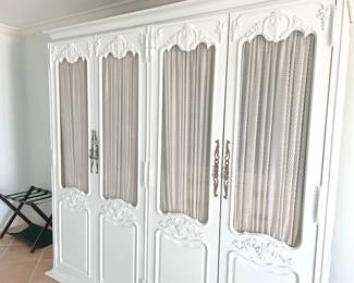 $300 Armoire -- This is a homemade armoire built around two tall cabinets (likely Drexel or similar). It separates in to (4) pieces – a base, topper, and two cabinets one of which has a built in, shell mirror. The outer doors have a very pale blue paint finish in the Shabby Chic style, with fine metal grill inset with gathered curtain on rod interior. Total measurement is 83”W x 21”D x 84”H.
