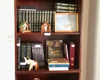 Bookshelf with encyclopedias, vintage wooden and plastic weather forecasters, onyx elephant, children's book and more.