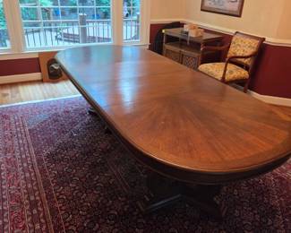 Solid wood Teak CUSTOM dining room table w/ two leaves inserted (gets smaller). Includes table cover/protector. Includes 6-8 solid wood chairs.