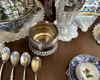 Silver spoons, bowl, antique sterling silver tea infusers and urn-shaped toothpick holders, a collection of silver spoons in a 19th Century EAPG C. Adams & Company Glass Factory "thousand eye" clear glass spoon holder; an antique Aynsley Porcelain imari pattern cup and saucer
