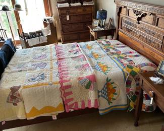 A gorgeous 1880’s Eastlake spoon carved walnut bed — headboard, footboard, and side rails; an 1880's Eastlake spoon carved walnut six-drawer chest of drawers, and another view of vintage and antique quilts - including hand made wedding ring quilt, a citrus fruit basket quilt with shades of orange, yellow, blue and green on white ground, a 1930s fan pattern quilt, a lovely vintage butterfly design quilt, and a "Sunbonnet Sue" quilt — plus beautifully framed antique photographs