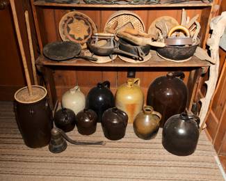 Antique and vintage cast iron cooking pans, vintage primitive carved kitchen tools and household tools, a collection of antique pottery jugs; vintage primitive wrought iron skillets, griddle and three-legged long handled pot; vintage Native American woven bowl/basket