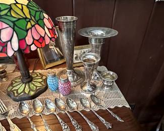 A selection of antique silver forks and spoons; silver trumpet form vases, a pair of EAPG Hobbs opalescent dot pattern silver topped salt and pepper shakers, and antique stained glass table lamp