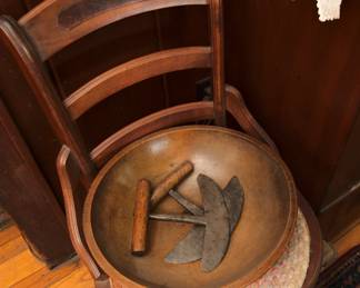 Closer view of one of the pair of late 19th century hip hugger ladder back chairs with cane seats, and an antique hand carved wooden bowl with three antique primitive herb choppers – hand forged iron with wood handles
