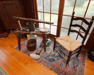 A marvelous primitive hand carved antique fruit press, a 19th century ladder back rush seat chair, antique glass fishing floats