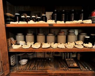 A closer look inside the cupboard at the antique medical and dental tools, dental casts, antique photographs, stoneware jars, vintage glass medicine/chemical bottles