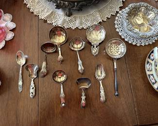 A delightful collection of antique silver tea caddy spoons and tea strainers
