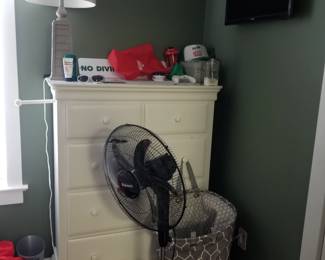 Tall dresser; table lamp; floor fan