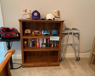 Bookcase, books, LSU baseball hats and Hornets baseball hats