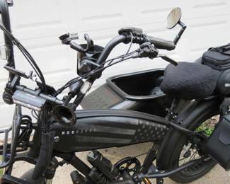 black electric "mud bike" with a sidecar, equipped with storage bags and a basket