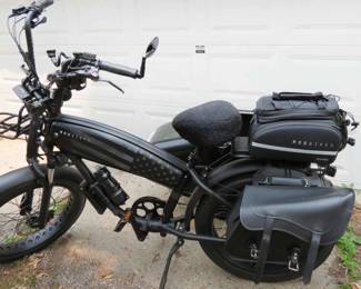 black electric "mud bike" with a sidecar, equipped with storage bags and a basket