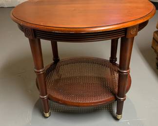 Oval wooden table with rattan bottom. The legs on this table have wheels. Asking $30. Note: There is a stain on the top corner of this table. See close up photo.