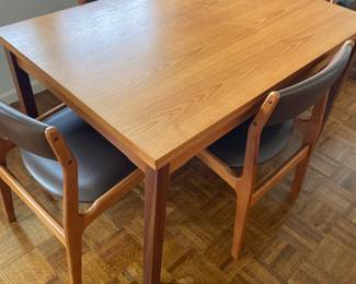 Rectangular MCM dining table with integrated extension on the ends of the table, shown with MCM wood and leather chairs