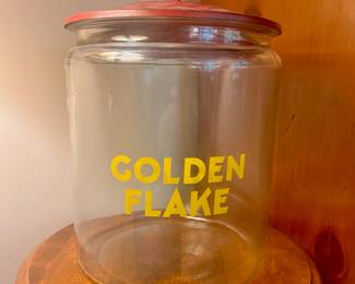 C135 - $200. 1950's Golden Flake Country Store Counter Jar with Red Metal Lid. Measures 12" tall x 9.5" wide. (Octagonal finial has a chip which is shown in the pictures)