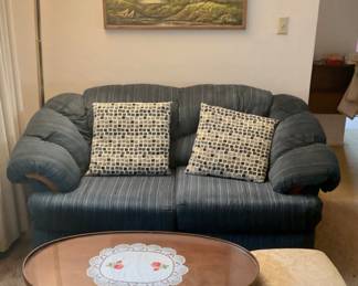 Small Sofa / Loveseat, Oval Wood Table w/Glass Insert, Gold Floor Lamp, Scenic Artwork, & Padded Foot Stool.