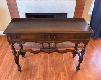 Price: $195
Elegant antique writing desk or console table featuring ornate carved stretcher, turned legs, and two small drawers with wooden knobs. Rich wood tone with classic proportions – perfect as a hallway table, entry console, or accent desk.
Shows some surface wear consistent with age but remains sturdy and full of vintage character.