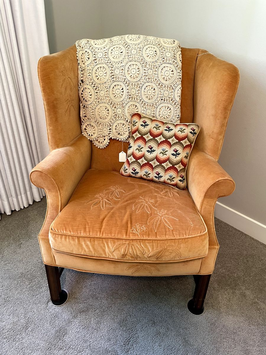Stitched vintage wingback chair, with cross stitched pillow, and throw.