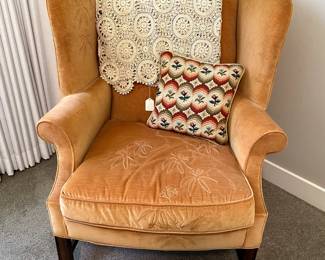 Stitched vintage wingback chair, with cross stitched pillow, and throw.