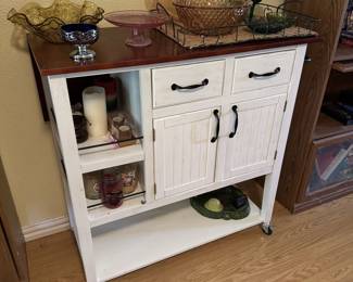White Wheel Island Cart with Expanding Top Holding Beautiful Colored Glassware Including Carnival Glass