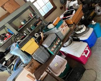 Large garage filled with various tools and other items, including several coolers, toolboxes, paint cans, automotive parts, metal shelving.
Heavy-duty workbench filled with miscellaneous tools and boxes.
