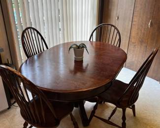 Solid wood oval dining table with pedestal base and medium-dark finish.
Set of four matching Windsor-back dining chairs with turned legs.