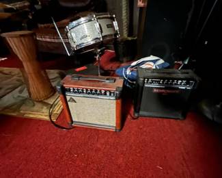 Musical instruments and music equipment. Pictured: Pair of guitar amps (Behringer and Behringer Vintage Series) with snare drum mounted on stand, djembe drum, and other music accessories.