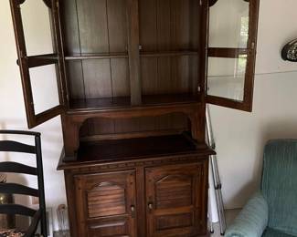 Dark wood hutch with upper glass cabinet doors, open center shelf, and lower paneled cabinet storage.