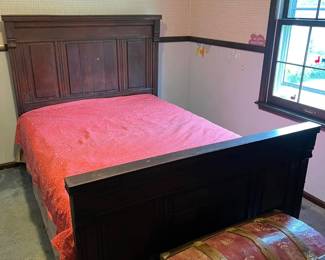 Antique dark wood full-size bed frame with tall paneled headboard and footboard.
Vintage steamer trunk with curved lid, metal hardware, and red floral patterned finish.