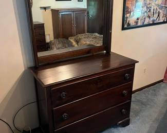 Antique dark wood dresser with three deep drawers and turned wooden knobs.
Attached framed mirror with side supports