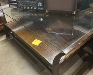 Heavy coffee table with glass top and plenty of room for books and magazines underneath.
