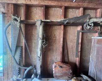 Located in the garage. Hand saws, bow saw, multiple crosscut saw, vintage framing square, cotton scales, two old irons, and other very old items. There is also a chest freezer located here.