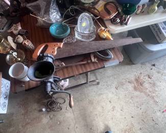 Located in garage. Vintage meat grinder, two hand saws, one hacksaw, several colored aqua colored bowls, Snoopy rod and reel, and an assortment of old collectables.