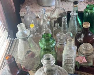 Located in garage. Several glass jugs, jars, and containers.