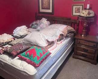 This is the queen bed and night stand that goes with the set. There is also decorative pillows along with bags of bedding and lots of handcrafted dollies. A vintage is on the night stand along with several wall pictures.