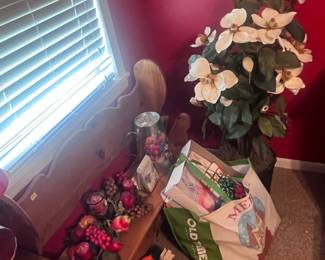 Located in red bedroom. Wooden bench with heart-shape cut into the back. There is also silk flower arrangements and a galvanized decorative water pitcher.