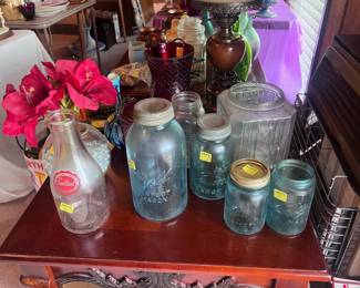 This table is located on the right side of the living room. There are several vintage blue fruit jar, a milk jar, old candy jar, a retro pottery vase, and several other items on this table. There are two end tables for sale like the one seen here. In addition, there are two Vanguard gas heaters located on the wall of the living room that are available to purchase. Both are in good working order.