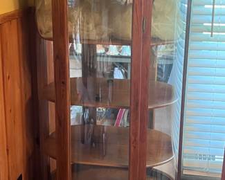 This rounded front curio cabinet is located in the dining area. Nice cabinet. I think its oak.