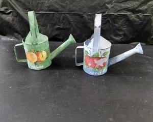 Small metal watering cans, hand-painted, some chipping showing.