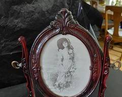 Antique looking, cherry color, round picture frame on hanging stand. Lots of detail on the frame with brass knob hangers holding it on a stand. Very unique and new condition.