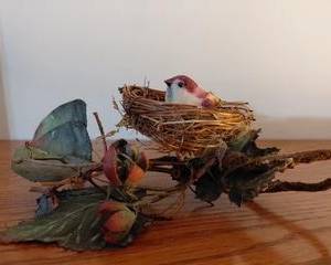 Small feathered bird nesting in a nest with decorative greenery, so sweet and detailed!