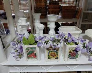 Small decorative white clay pots filled with purple orchids, labels read "watermelon, sunflowers, pansy", beautiful small decor for any space.