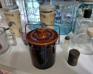 Vintage Small Brown Stoneware jar with lid and metal clasp., has a small chip on the bottom that cannot be seen while sitting on counter.