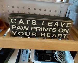 A Wooden Plaque with "Cats Leave Paw Prints on Your Heart" black with white lettering.