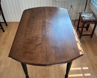 R20 - $125 - Round Wood Drop Leaf Dining Table. Chairs not included. The table is in great condition! With natural wood finish on top and black painted legs. Measures 42" round and 26"W when dropped.
