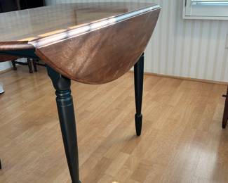 R20 - $125 - Round Wood Drop Leaf Dining Table. Chairs not included. The table is in great condition! With natural wood finish on top and black painted legs. Measures 42" round and 26"W when dropped.